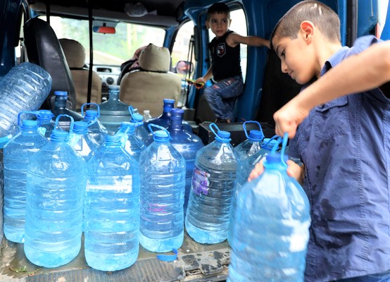 水不足により湧き水をペットボトルに溜めて持ち帰る家族。(レバノン、2021年8月撮影)