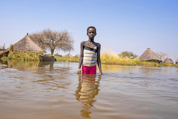 洪水の被害にあったジョングレイ州の村で、浸水した道の上に立つ12歳の子ども。(南スーダン、2022年1月撮影)