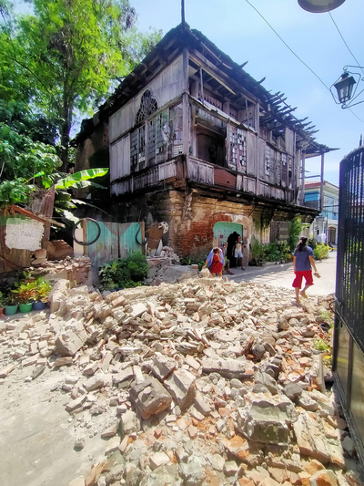 マニラ北部で、地震により崩れた家の瓦礫のそばを歩く人たち。(フィリピン、2022年7月27日撮影／AFP)