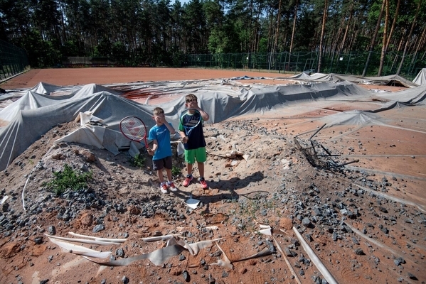 砲撃や爆撃を受けて破損したテニスコートに立つ子どもたち。このテニスコートで、テニスの大会が行われる予定だった。(ウクライナ、2022年6月撮影)