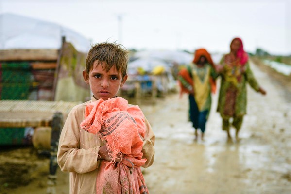 バロチスタン州・Naseerabad地区の村が洪水に遭い、荷物を持って安全な地域に移動する子ども。(パキスタン、2022年8月18日撮影)