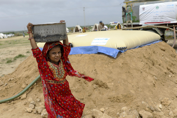 シンド州・Thatta地区の避難所で、ユニセフが設置した給水タンクから水を汲み、滞在するテントに戻る途中の9歳のアーシアさん。(パキスタン、2022年8月28日撮影)