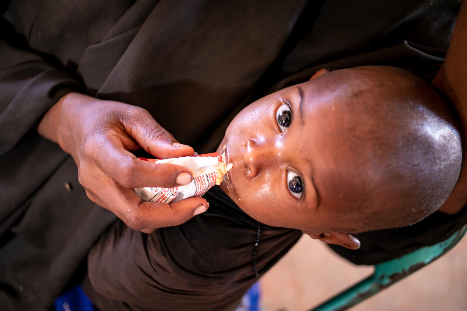 ドロー避難民キャンプ内にある保健センターで、ユニセフ支援物資の栄養補助食を食べる幼い子ども。（ソマリア、2022年2月3日撮影）