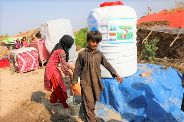 シンド州の洪水の被害を受けた村で、ユニセフが設置した給水タンクから安全な飲み水を手に入れた10歳のピヤーさん。(パキスタン、2022年9月11日撮影) 