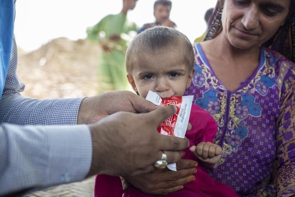 シンド州で洪水により道路が浸水し孤立した村の保健キャンプで、重度の急性栄養不良と診断され、すぐに食べられる栄養治療食(RUTF)を食べさせてもらう1歳のサナムちゃん。(パキスタン、2022年9月26日撮影)