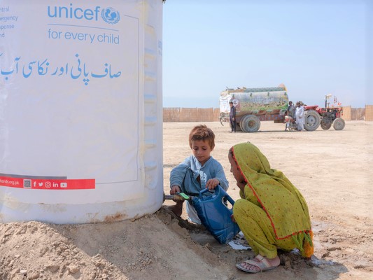 バロチスタン州から37世帯が避難した一時避難所で、ユニセフが支援した給水タンクからきれいな水を汲む子どもたち。(パキスタン、2022年9月15日撮影)