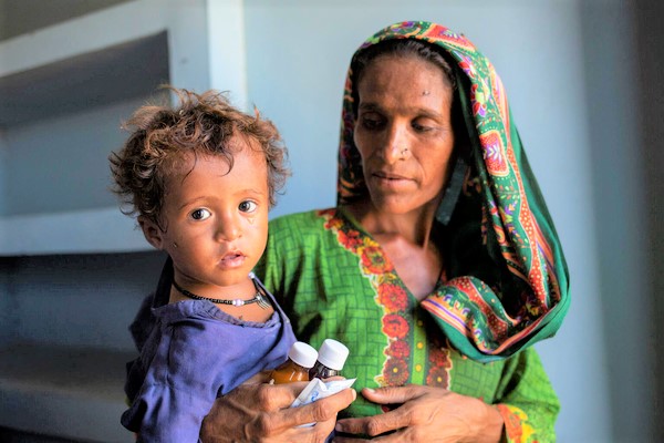 高熱と下痢の症状で訪れた保健ケア施設で、薬を受け取った2歳のナビラちゃん。(パキスタン、2022年9月26日撮影)