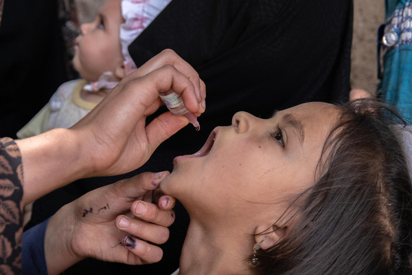 ヘラートの自宅まで、経口ポリオワクチンの投与を受ける女の子。(アフガニスタン、2022年5月撮影)