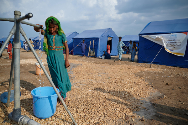 シンド州の医療緊急キャンプの給水所で、ユニセフが支援した衛生物資のバケツに水を汲む8歳のギートゥさん。(パキスタン、2022年9月14日撮影)