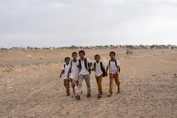 学校まで長い距離を、太陽の暑さと風の中歩く子ども立ち。(イエメン、2022年1月撮影)