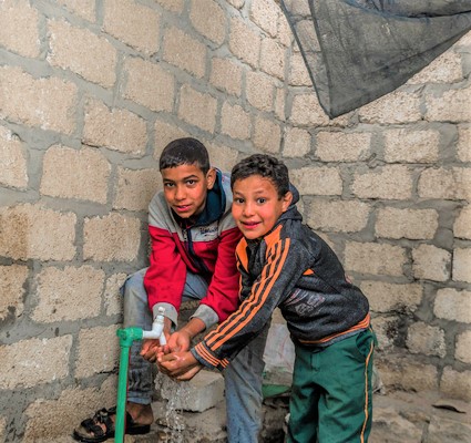 ファイユーム州の村で、自宅に設置された水道を使う子どもたち。エジプトは年間約70億㎥の水不足に直面している。(エジプト、2022年1月撮影)