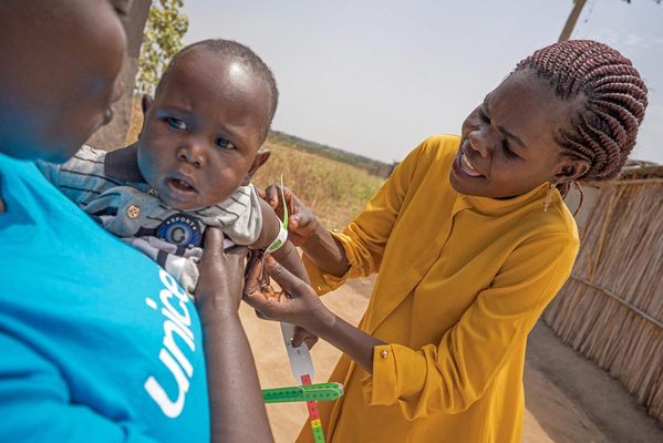 ジュバで、ユニセフの栄養スタッフから上腕計測メジャーの使い方を教わり、生後8カ月の息子の栄養状態を確認する母親。(南スーダン、2022年2月撮影)