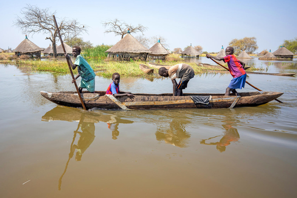 ジョングレイ州で、洪水により浸水した村の中をカヌーに乗り移動する子どもたち。(南スーダン、2022年1月撮影)