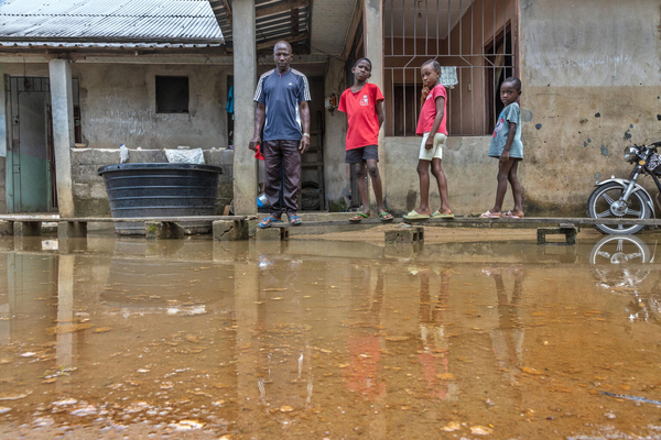 バイエルサ州で、浸水した自宅の前に作った仮設通路を使う家族。(ナイジェリア、2022年10月4日撮影)