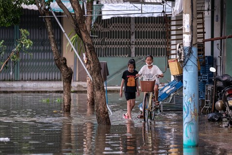クアンナム省にある町で、台風の影響により浸水した道を通る子どもたち。(ベトナム、2022年9月撮影)