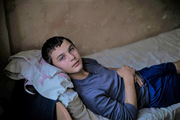 リヴィウの小児科病院のベッドに横たわる12歳のミハイロさん。自宅の庭にロケット弾が落ち、父親は亡くなった。ミハイロさんも負傷し、頭には2つの破片が刺さった状態でいる。(ウクライナ、2022年9月撮影)