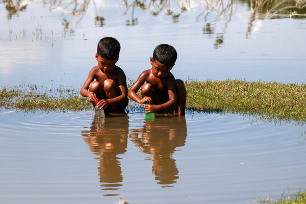 南部にあるベンガル湾で、サイクロンの影響により浸水した場所から、生活に使える物を探す子どもたち。(バングラデシュ、2022年10月25日撮影)
