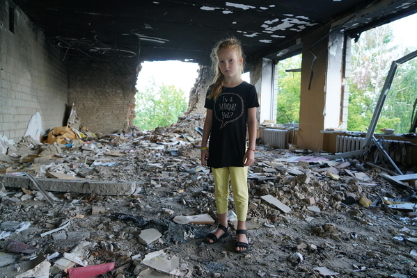 2～3月の間で14回もの砲撃やロケット弾の攻撃を受け、破壊された学校の瓦礫の中に立つ8歳のアーニャさん。(ウクライナ、2022年7月撮影)