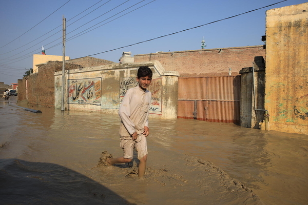 カイバル・パクトゥンクワ州で、大洪水の影響により浸水した道を歩く子ども。(パキスタン、2022年8月撮影)