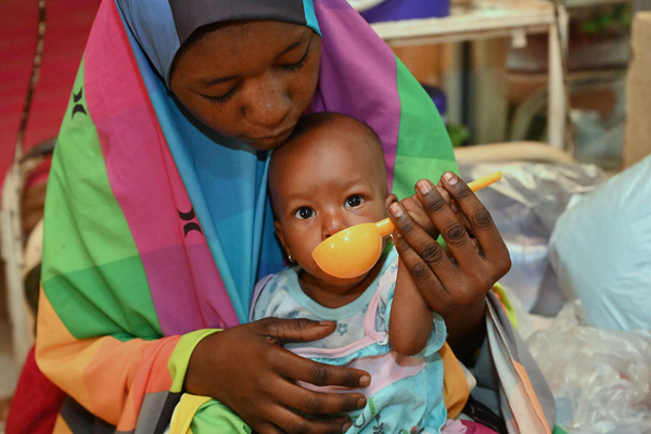 タウア州で栄養補助食を母親に食べさせてもらう、栄養不良で生後8カ月のフォージアちゃん。(ニジェール、2022年8月撮影)