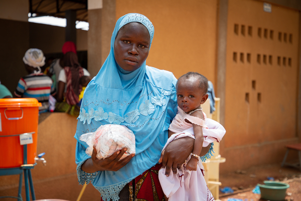 重度の急性栄養不良で生後6カ月のアブドゥルちゃんを抱く母親。カヤの保健センターで、子どもの栄養治療食のプランピーナッツを受け取った。(ブルキナファソ、2022年6月撮影)
