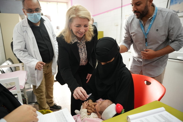 プライマリ・ヘルスケア・センターで、赤ちゃんに経口ワクチンを投与するラッセル事務局長。(2022年12月6日撮影)