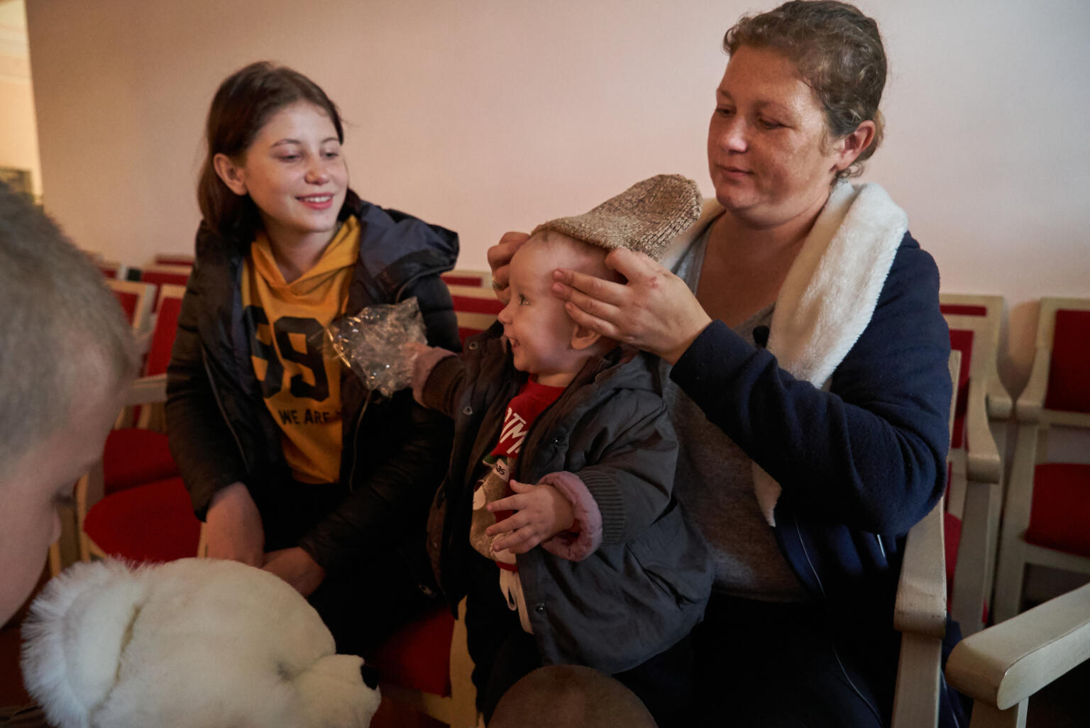 暖かい衣類、靴、毛布、おもちゃが入った、ユニセフの子ども用冬物キットを受け取った母親のカテリーナさんが、生後10カ月のボーダンちゃんに着せています。（ウクライナ、2022年10月9日撮影）