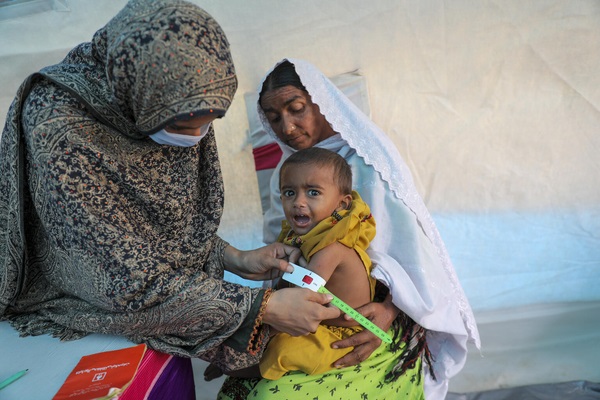 バルチスタン州の国内避難民キャンプの中のユニセフが支援する栄養施設で、上腕計測メジャーを使った検査により、重度の急性栄養不良と診断された1歳のアウェイスちゃん。(パキスタン、2022年11月撮影)