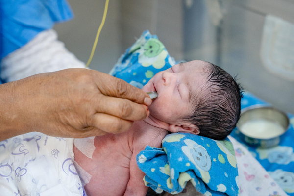 カトマンズの産婦人科病院の新生児集中治療室(NICU)で、ミルクを飲む生まれたての赤ちゃん。(ネパール、2022年8月撮影)