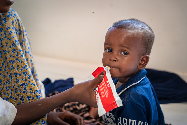 プントランドの病院にある急性栄養不良を治療するセンターで、すぐに食べられる栄養治療食(RUTF)を母親に食べさせてもらう1歳のアドブラちゃん。(ソマリア、2022年10月撮影)
