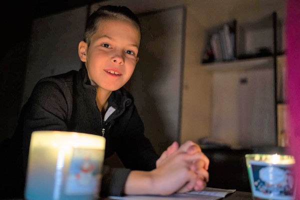 ブチャで、キャンドルの明かりを使って宿題をする11歳のティモフェイさん。日中は空襲のサイレンが鳴り、学校の授業が中断されることも多い。(ウクライナ、2022年11月撮影)