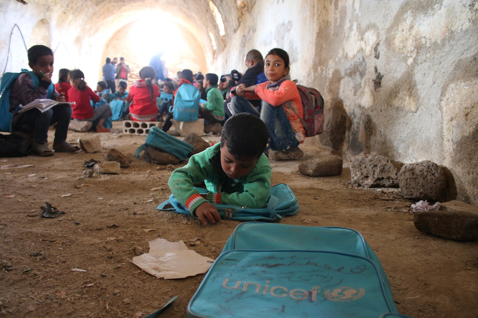 紛争下のシリアでは、子どもたちが学習を継続できるよう、防空壕の中に仮設教室がつくられた。熱心にノートを書く男の子。（シリア）