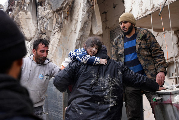 北西部にあるアレッポのアフリーンの農村部で、地震により倒壊した建物の瓦礫から小さな子どもを救助する地域住民たち。(シリア、2023年2月6日撮影／AFP)