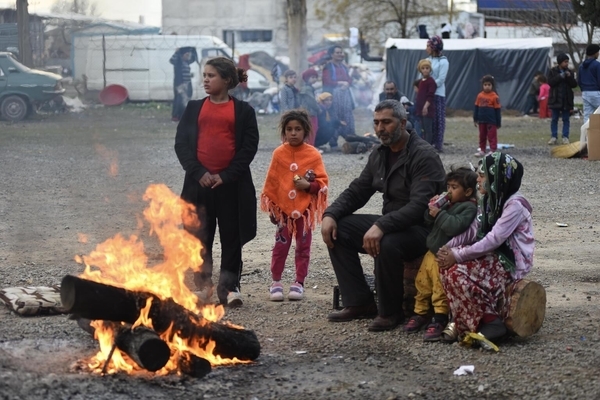 カフラマンマラシュの仮設住居の外にある焚火で暖を取る家族。地震の影響により、一家の自宅はひどく損壊した。(トルコ、2023年2月10日撮影)
