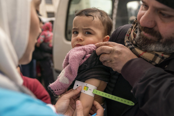 ユニセフ移動式保健チームのスタッフから、上腕計測メジャーを使った栄養検査を受ける2歳のソンドスちゃん。(シリア、2023年2月10日撮影)