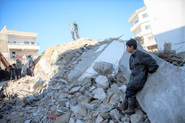北西部のラタキアで、地震により倒壊した建物の瓦礫によりかかる男の子。(シリア、2023年2月8日撮影)