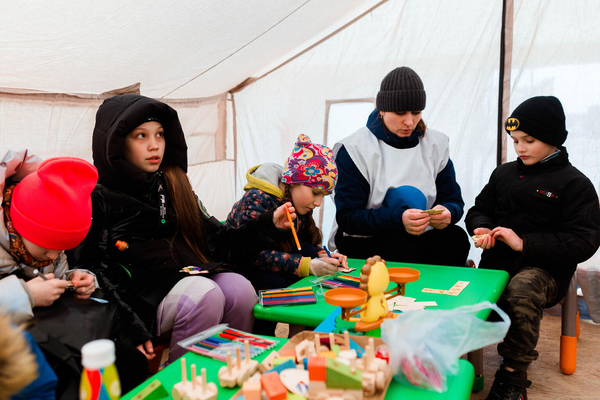 ウクライナの戦闘を逃れて隣国に避難してくる子どもたちや家族は後を絶ちません。ユニセフはパートナー機関と協力し、ウクライナとの国境付近に、ウクライナ難民の子どもと家族のための支援拠点「ブルードット」を設置しています。写真はモルドバのブルードット内の「子どもにやさしい空間」で、スタッフが見守る中、遊ぶ難民の子どもたち。（モルドバ、2022年3月撮影）