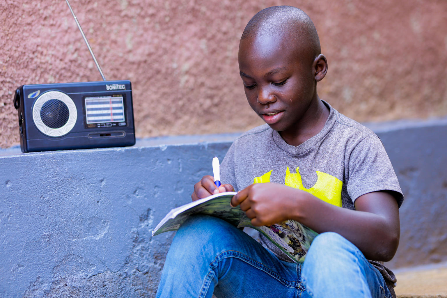 新型コロナによる学校閉鎖のため、自宅で学習しているケビンさん（11歳）。毎日ラジオで小学校5年生の授業を聞いている。（ルワンダ、2020年4月撮影）