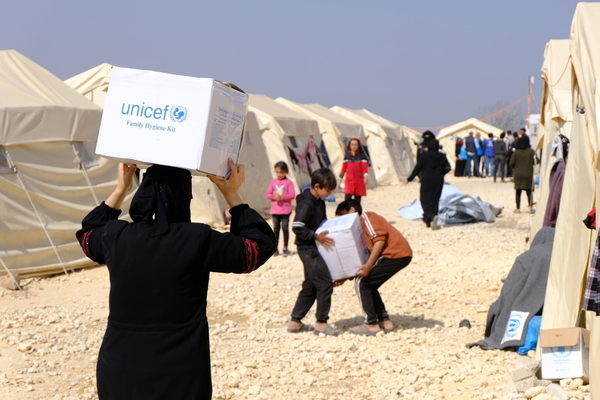 難民キャンプで、ユニセフの衛生用品を受け取り、テントまで運ぶ子どもたち。(シリア、2023年3月1日撮影)