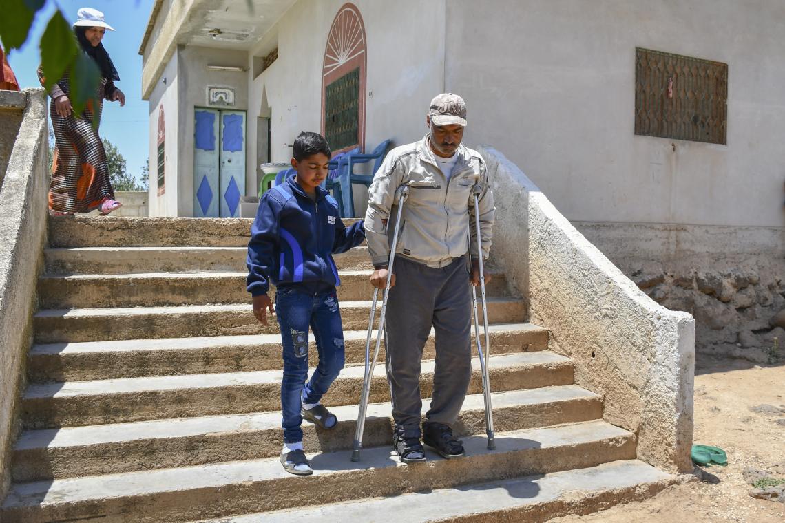 建設現場でおったケガで足が不自由な父親のモハメッドさんに寄り添い、階段を降りるのを助けるアフマド（シリア、2022年5月24日撮影）