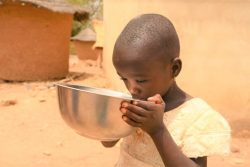 北部の村で、ユニセフの支援で設置された太陽光発電式の水道から汲んだ水を飲む子ども。(コートジボワール、2023年3月7日撮影)