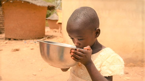 北部の村で、ユニセフの支援で設置された太陽光発電式の水道から汲んだ水を飲む子ども。(コートジボワール、2023年3月7日撮影)