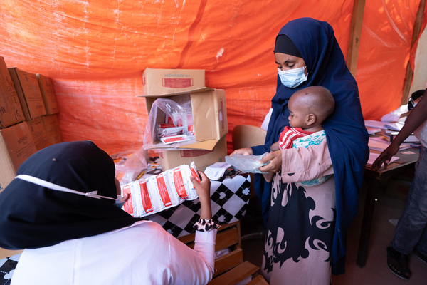 ユニセフが支援する栄養施設で、すぐに食べられる栄養治療食(RUTF)を受け取る親子。(ソマリア、2023年2月8日撮影)