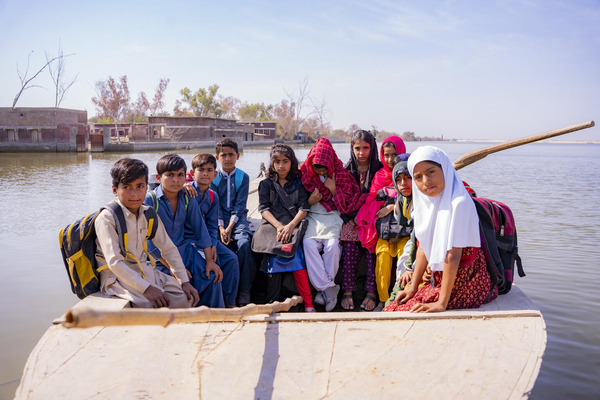 洪水の被害にあったシンド州の村で、未だに水が引かず学校までボートに乗って通学する子どもたち。(パキスタン、2023年3月11日撮影)