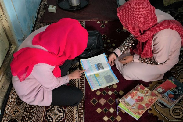 教員の父親から勉強を教わる高校2年生のアイシャさん。(アフガニスタン、2023年3月19日撮影)