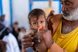 アデンの国内避難民キャンプで、すぐに食べられる栄養治療食(RUTF)を父親に食べさせてもらう子ども。(イエメン、2023年1月撮影)