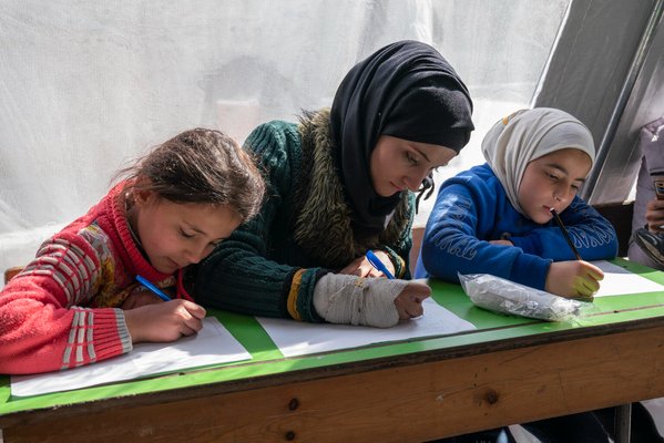 避難所のテントに設けられた教室で勉強する子どもたち。