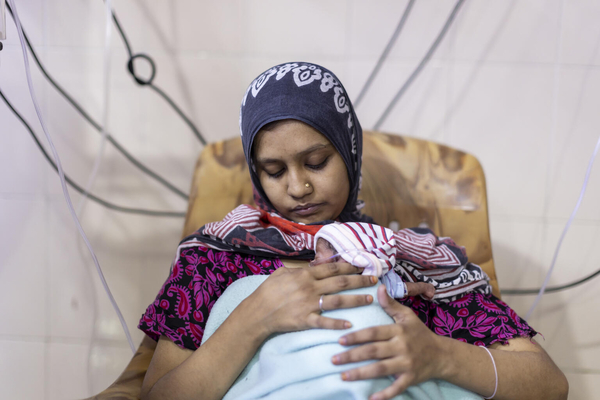 テランガナ州にある病院の新生児集中治療室(NICU)で、早産により低体重で生まれた赤ちゃんを抱く母親。(インド、2022年7月撮影)