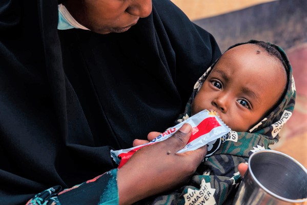 ガリッサの病院で、すぐに食べられる栄養治療食(RUTF)を母親に食べさせてもらう1歳のマンスールちゃん。(ケニア、2022年12月撮影)