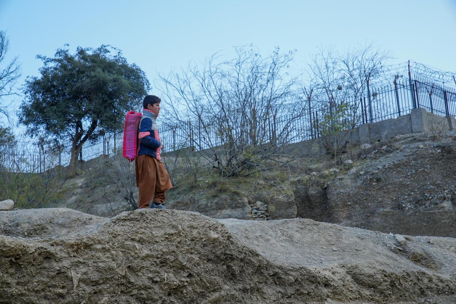 パキスタンからアフガニスタンへ、歩いてトールハム国境を越える男の子（2022年12月13日撮影）
